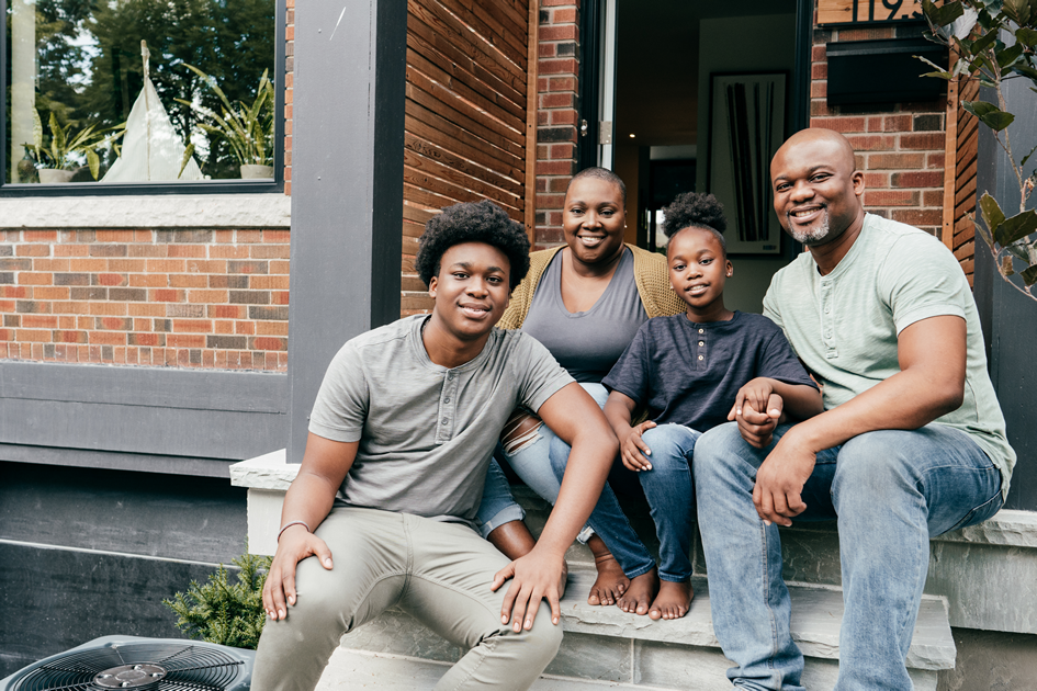 Photo d’une famille de quatre personnes assises sur le porche de leur logement